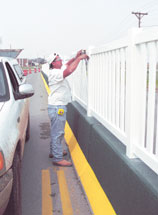 Jim Tucker of Ozark Vinyl Products in Neosho installs the classic picket fence atop the Duquesne wall barrier. The wall was constructed to stop pedestrians from jaywalking.
