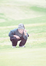 Tug Baker, senior, reads the green on the 18th hole at the Crossroads tournament.

