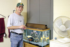 Mike Pittman, sophomore psychology major, feeds fish in his Blaine Hall room. Pittman is 44 years old and plans to attend graduate school.
