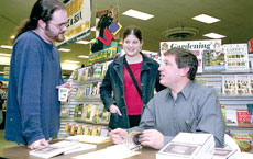 Dr. Arthur Saltzman (seated) signs copies of one of his books.
