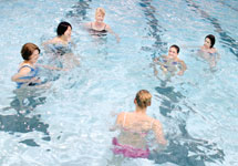 Kim Boessen, bottom, leads her Tuesday water aerobics class through some warmup exercises.
