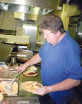 Jim Alderman, LionÂ´s den grill cook, prepares the dayÂ´s first meals.
