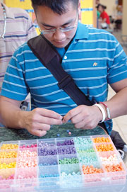 As part of the Homecoming week activities, students had the opportunity to have their name written on a piece of rice and make novelty necklace around it. Jerome Doan, junior pre-pharmacy major participates in the event Sept. 28.
