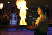 Josh Dennis, server at Mythos Euro Greek Kuzina, holds a flaming kasseri cheese dish. Mythos is located at 1306 Range Line Rd. and is open Monday through Saturday.
