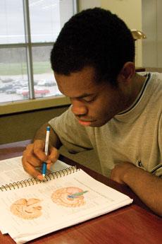 Joshua Onuiri looks over his books as he studies biology in Spiva Library on April 4.
