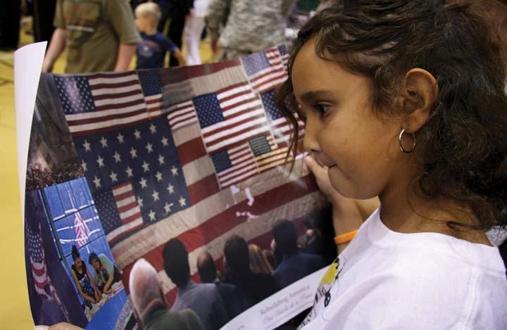 Brooklyn Jusino, tornado survivor, looks at a poster of the National 9/11 Flag, which she placed stitches in on the flag’s final stop Sunday. The flag is going to be displayed at the National September 11 Memorial and Museum.
