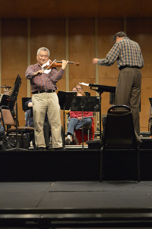 Violinist Chin Kim, left plays as Dr. Kexi Liu conducts the orchestra during rehearsal Wednesday night for the La Musica Italiana performance in Taylor auditorium, Friday, Nov. 8, 2013