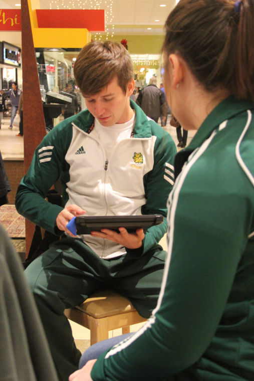 Senior Jessi Nelson and junior Amanda Sussy use an iPad for transactions at the Spirit Squad Bookstore located inside Northpark Mall on Nov. 23.