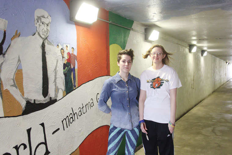 Sara Humphries and Kristen Stacy pose in front of the tunnel mural