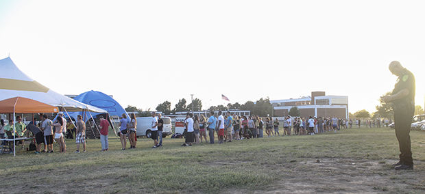 In a line that faded into the sunset, students wait for their turn in the zombie themed laser tag tent while campus police Chief Ken Kennedy, keeps a vigilant post on Friday, Aug. 22 at the cross country track.