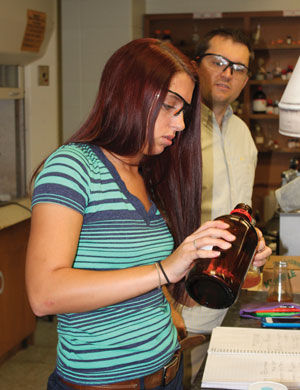 Senior biochemistry major Lauren Sanders, with the help of her adviser Dr. Elliot Ellis, measures out the chemicals needed to test compounds featured in her senior thesis project over ionic liquids in Reynolds Hall on Sept. 8.